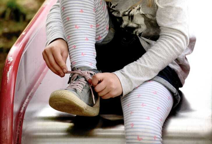 子供がひも付きの靴を履いている画像