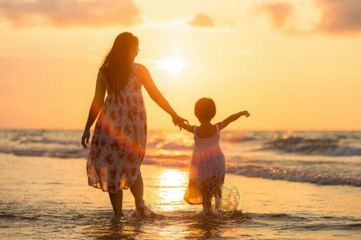 子供と海を楽しむ母親の後ろ姿