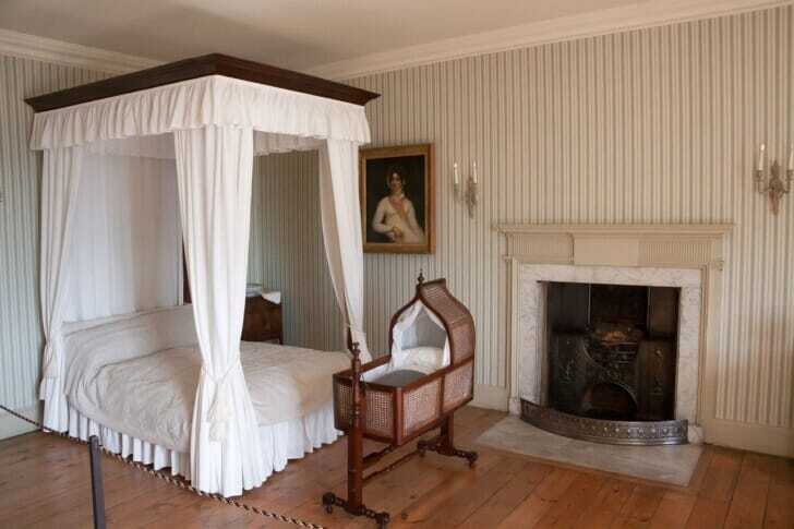 洋室に白いカーテンに覆われた天蓋付きベッドがある写真