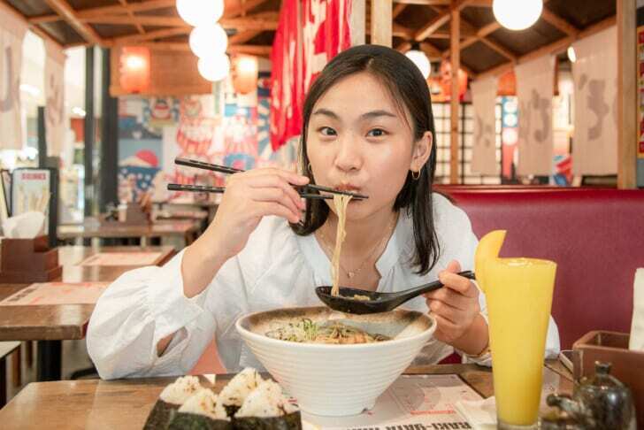 福岡名物のとんこつラーメンを食べる女性の写真