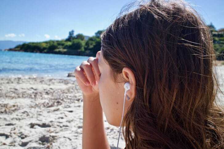 イヤホンで音楽を聴いている女性の写真