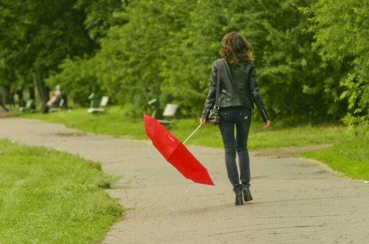 折りたたみ傘を持った女性の後姿の画像