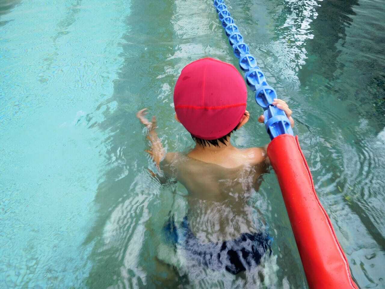 水泳帽をかぶって泳いでいる小学生の写真