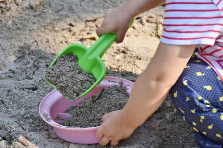 砂場でおもちゃを使って遊んでいる子供の写真