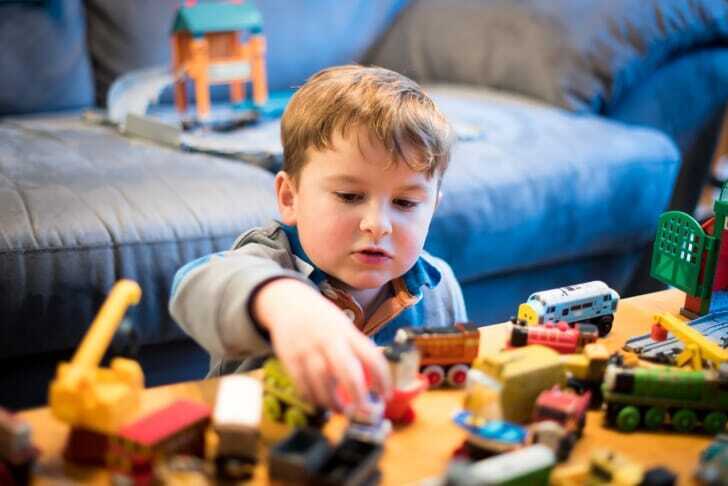2歳くらいの男の子が電車のおもちゃで遊んでいる写真