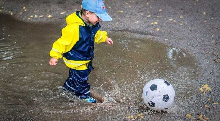 レインコートを着てサッカーをする子供の画像