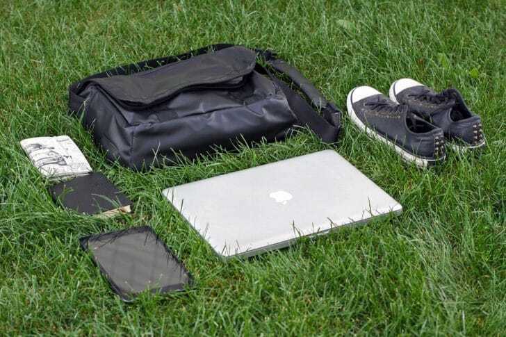 芝生の上にバッグやパソコン、靴が置いてある写真