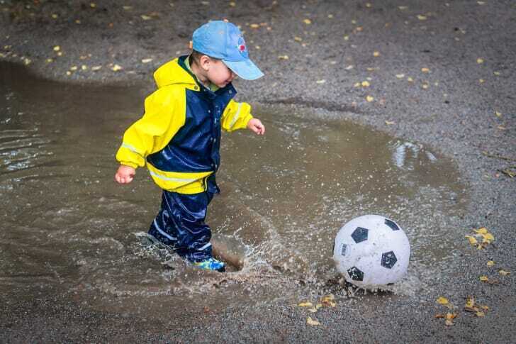 水たまりの中ボールを蹴る子供の写真
