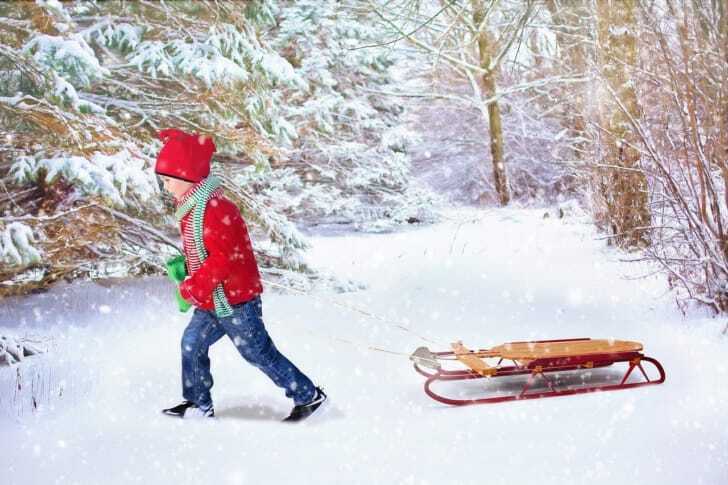 雪の中をそりを引いて歩く子供の写真