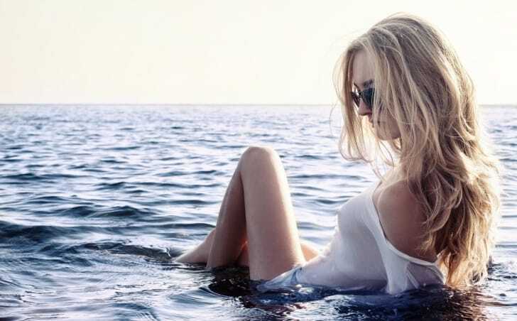 ラッシュガードを着て海に入っている女性の写真