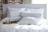 真っ白な寝具で作られたベッドルームの写真