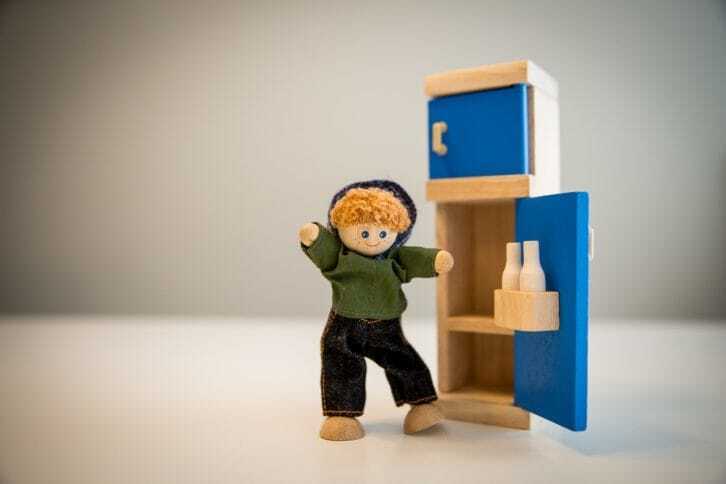 木製の冷蔵庫と人形の男の子の写真