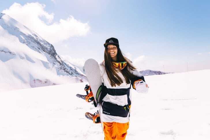 ゲレンデでスノーボードを片手に笑顔の女性の写真