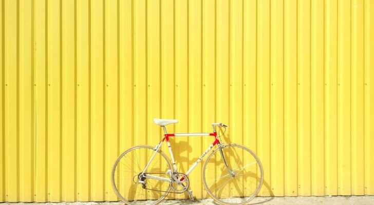 黄色い壁に立てかけられた白い自転車の写真