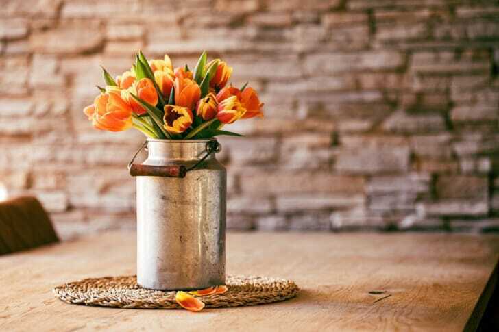 オレンジの花が挿してある花瓶の写真
