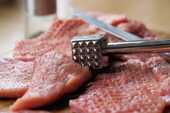 肉たたきを使って生肉を調理している画像