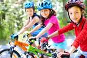3人の子供がヘルメットをかぶり自転車に跨ぐ写真
