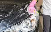 スポンジと洗剤で車を洗っている画像