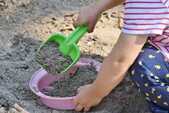 砂場でおもちゃを使って遊んでいる子供の写真