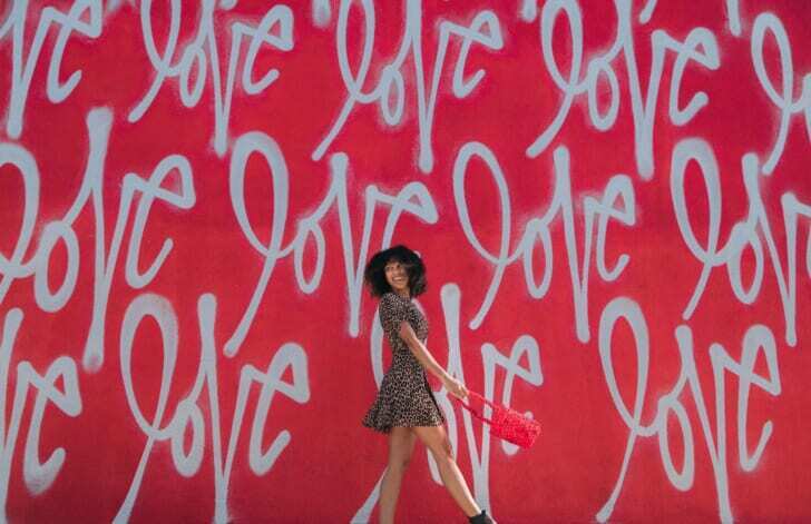 loveというグラフィティが描かれた壁の前に立つ女性の写真