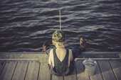 釣りをしている男の子が座っている後ろ姿の画像