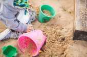 砂場で子供がバケツで遊ぶ写真