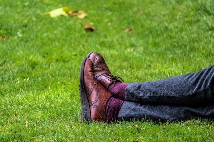 革靴を履いた人が芝生でくつろぐ写真