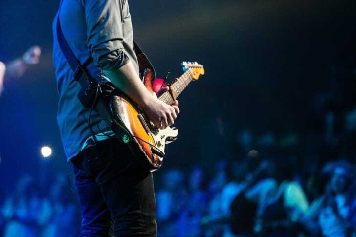 ライブハウスでギターを弾いている人の後ろ姿の写真