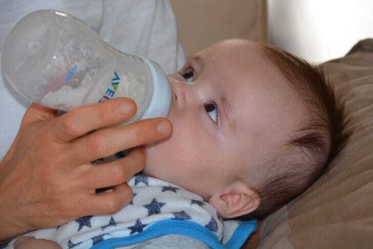 赤ちゃんが哺乳瓶からミルクを飲んでいる写真