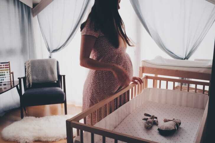 妊娠中の女性とベビーベッドの写真