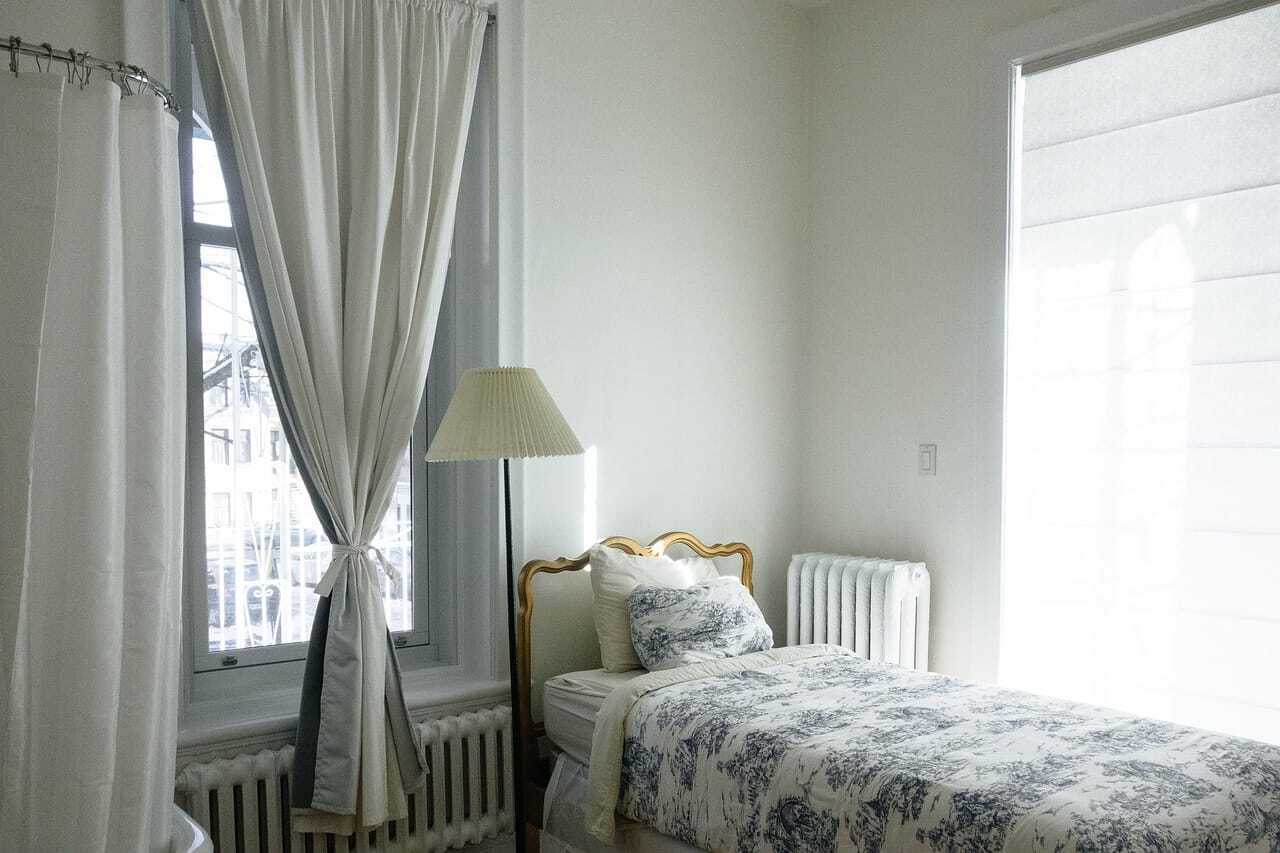白い壁とカーテンの部屋のベッドの写真