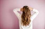 woman in white long-sleeved shirt standing in front of pink wall